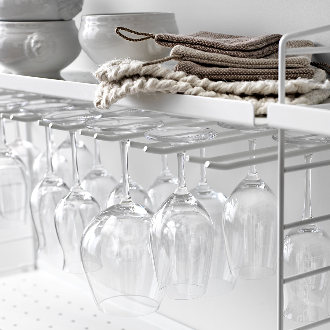 Elegant clear glassware on a white shelving unit, paired with natural-toned dish towels and textured dishware.