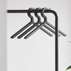 Four sleek black hangers on a minimalist black rack, set against a soft white background. Perfect for modern spaces.