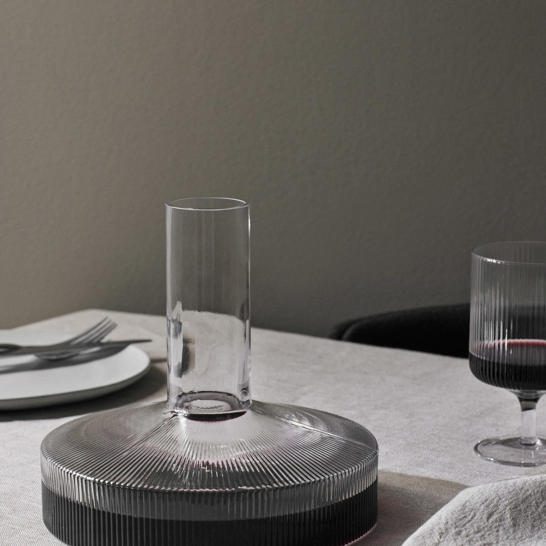 Clear glass vase with ribbed patterns, featuring a gradient of transparent to dark gray against a neutral background.