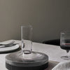 Clear glass vase with ribbed patterns, featuring a gradient of transparent to dark gray against a neutral background.