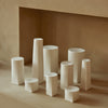 Assorted white ceramic vases in varying shapes and sizes against a soft beige background. Elegant, minimalist design.