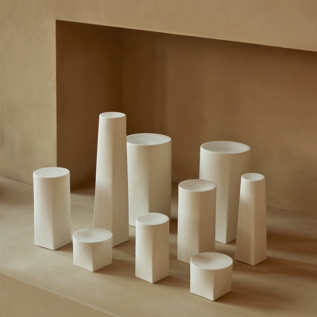 Neutral-toned geometric vases in various shapes and sizes, featuring smooth, matte finishes against a soft backdrop.
