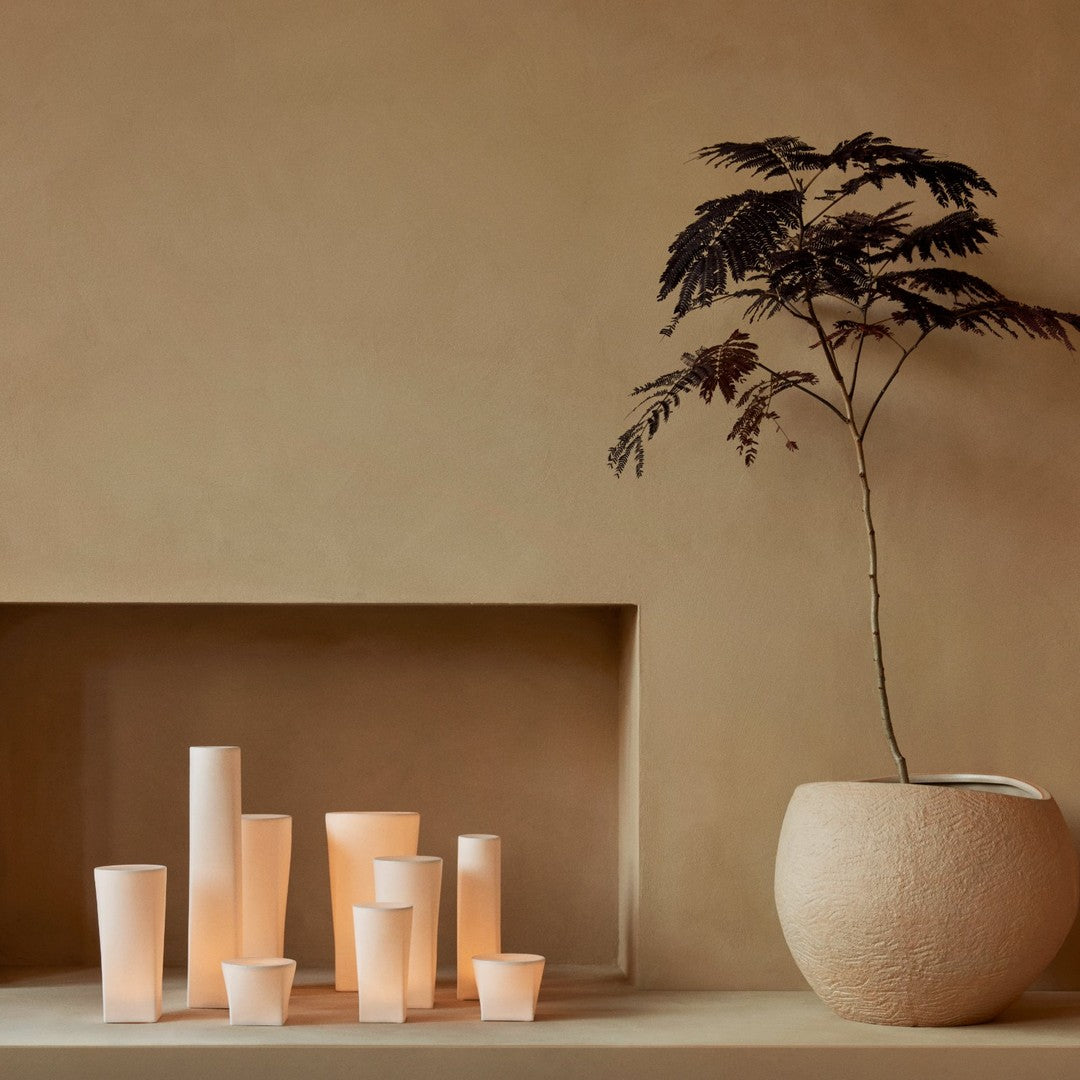 Soft beige backdrop with cream and amber candle holders creating a serene, harmonious display.