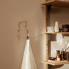 Sleek gold wall hook against a warm taupe backdrop, paired with a textured cream towel for a stylish, modern look.