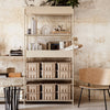 Beige shelving unit with a minimalist design, featuring multiple light tan storage bins and a textured neutral wall backdrop.