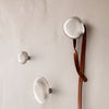 Sleek silver wall hooks in varying sizes, featuring a minimalist design against a neutral wall background.