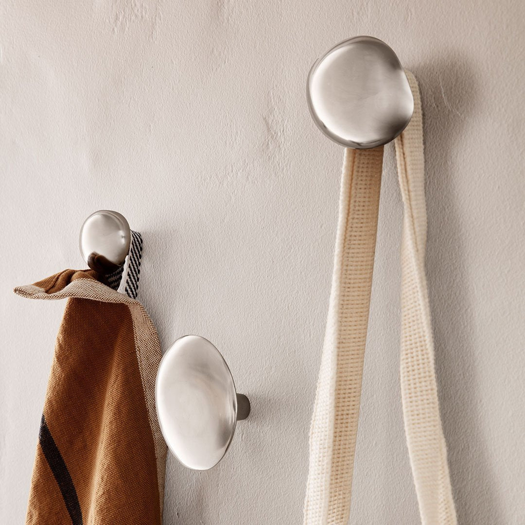 Modern metallic wall hooks with beige and brown fabric hanging, showcasing a minimalist design. Perfect for any decor.