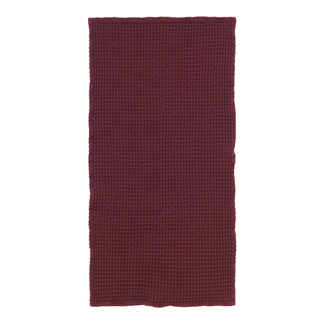 Deep burgundy fabric with a subtle checkered pattern, adding texture and warmth to any space.