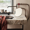 Elegant oval mirror with a gold finish against a rustic stone sink, complemented by earthy brown and white accents.