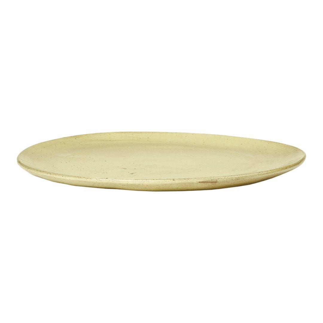Light yellow, smooth, round serving plate with a simple, minimalist design and subtle variations in texture.