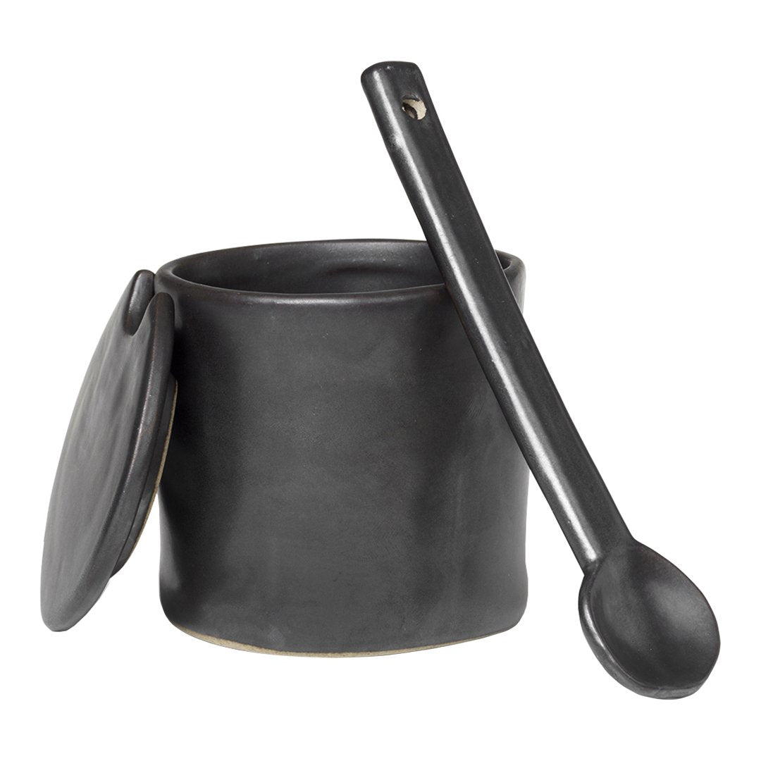Black ceramic jar with a smooth matte finish and matching spoon, featuring a minimalist design.