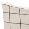 Beige fabric pillow with black grid pattern and frayed edges. Perfect for a modern, cozy decor style.