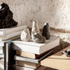 Textured vases in gray, white, and black, displayed on stacked books, showcasing earthy tones and unique patterns.