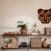 Neutral wall with colorful dots, brown leopard wall decor, earthy tones in planters and shelves, modern minimalist design.