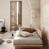 Neutral beige bedding with striped brown accents, complemented by a soft gray backdrop and natural wooden elements.