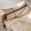Beige textured throw blanket and pillow with a dark stripe pattern, creating a cozy and modern aesthetic.