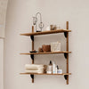 Wooden shelving unit with a warm brown finish, featuring beige towels and woven baskets against a neutral wall.