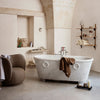 "Elegant beige marble bathtub with soft brown towel, styled in a neutral-toned minimalist bathroom setting."