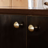 Black cabinet with gold accents; sleek design featuring round, matte black and shiny gold door knobs.