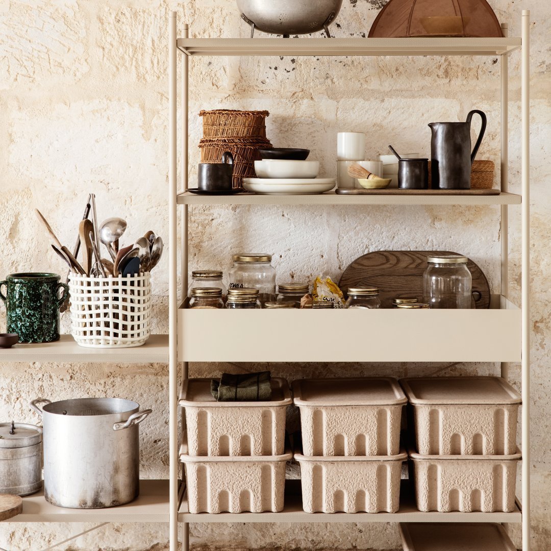 "Neutral earthy tones and textured patterns on kitchen organizer shelves with glass jars and woven baskets."