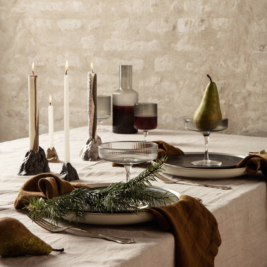 Elegant table setting with neutral shades, textured linens, dark glassware, and warm brown accents. Perfect for gatherings.