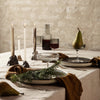 Elegant table setting with neutral shades, textured linens, dark glassware, and warm brown accents. Perfect for gatherings.