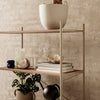 Wooden shelves with neutral tones, featuring white, green, and black accents against a textured beige wall.