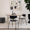 Minimalist round dining table with natural wood finish, sleek black chairs, and soft neutral decor accents.