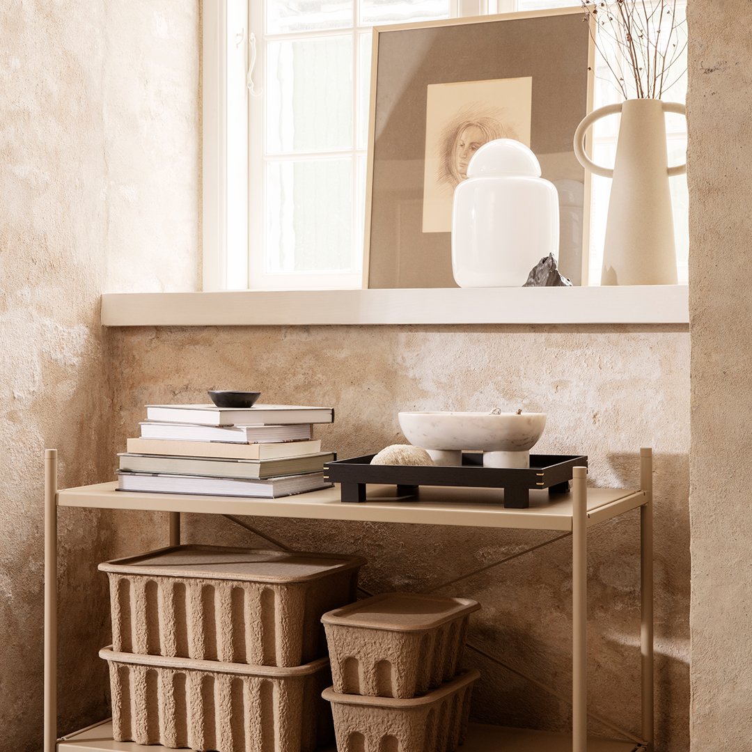Neutral beige tones with layered books, black tray, and textured tan baskets enhance a minimalist decor.
