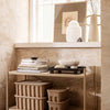 Neutral beige tones with layered books, black tray, and textured tan baskets enhance a minimalist decor.