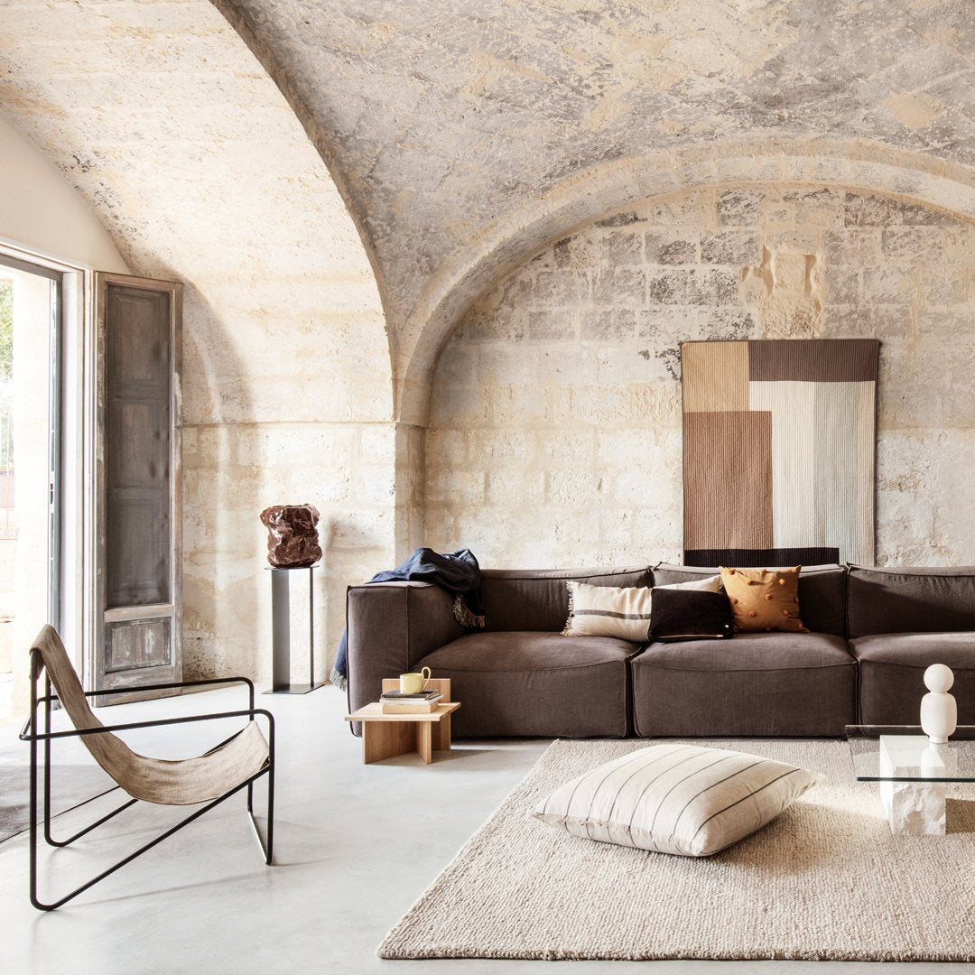 Brown sectional sofa with earthy tones, beige geometric patterns, and a light neutral rug for a modern, chic look.