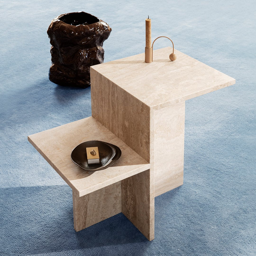 Stylish beige stone side table with geometric design, paired with a black decorative bowl and subtle blue backdrop.