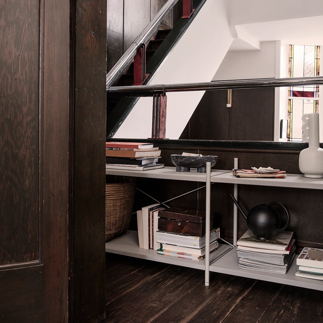 Modern shelving unit with sleek silver accents, white surfaces, and rich dark wood contrasting with minimal decorative elements.