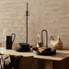"Minimalist black tableware with natural textures, warm tones, and earthy accents against a rustic beige background."