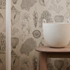 Beige wallpaper featuring detailed illustrations of coral and sea plants in natural tones, complemented by a light-colored planter.