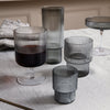 Set of ribbed gray glasses with varying heights and shapes, showcasing a modern and elegant design on a textured surface.
