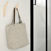Light gray tote bag with black and cream striped handles, modern minimalist design.