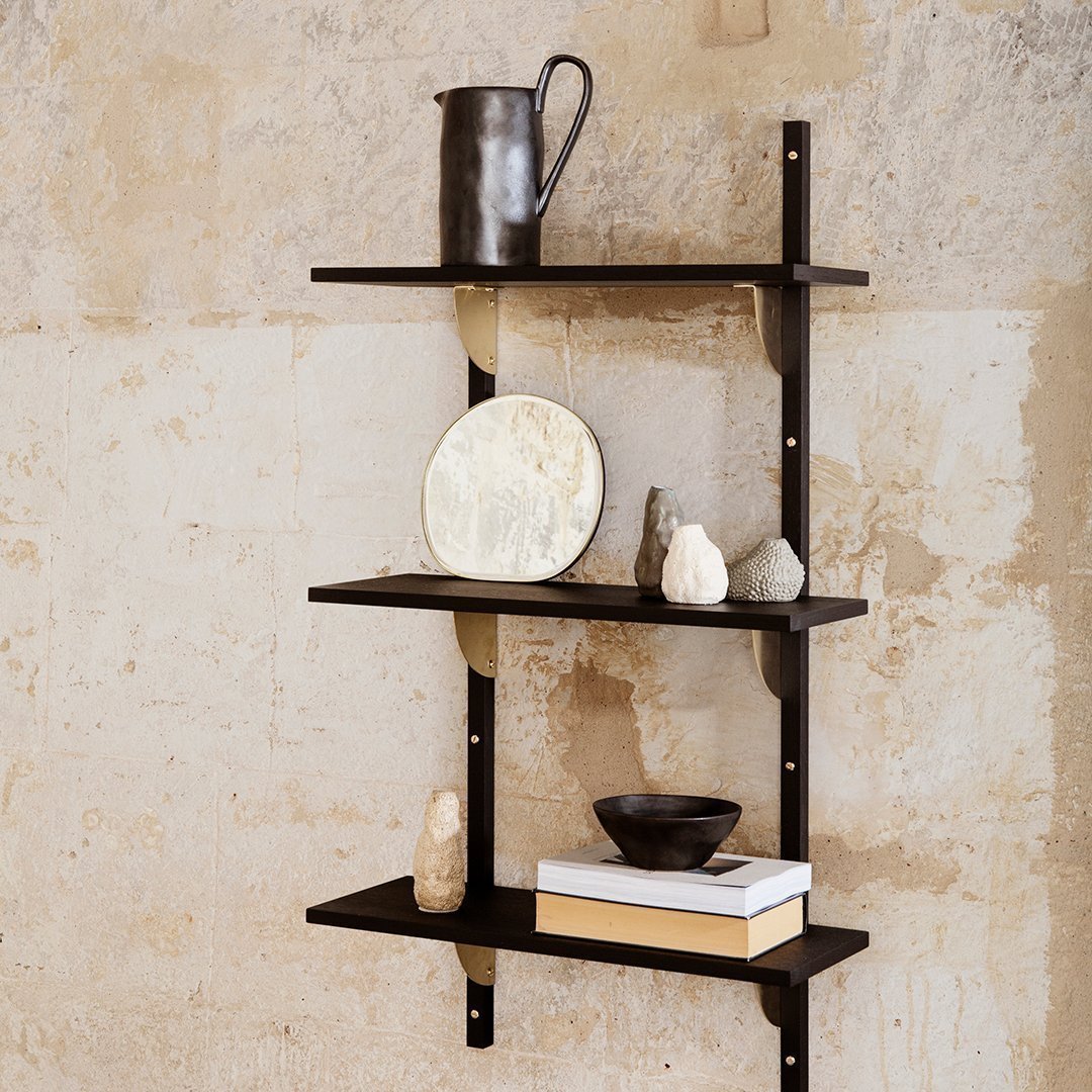 Black shelving unit with sleek lines and neutral decor against textured beige wall.
