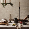 Rustic table setting with warm earth tones, soft beige linens, black ceramic, and greenery accents.