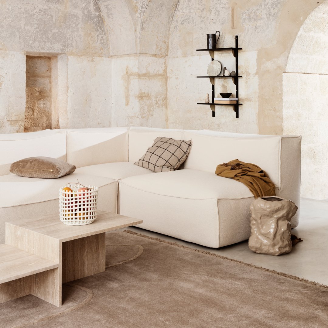 Beige sectional sofa with plaid and solid throw pillows, light wood coffee table, and textured beige rug.