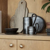 Black ceramic tableware with a matte finish, featuring elegant curves and minimalist design against wooden surfaces.