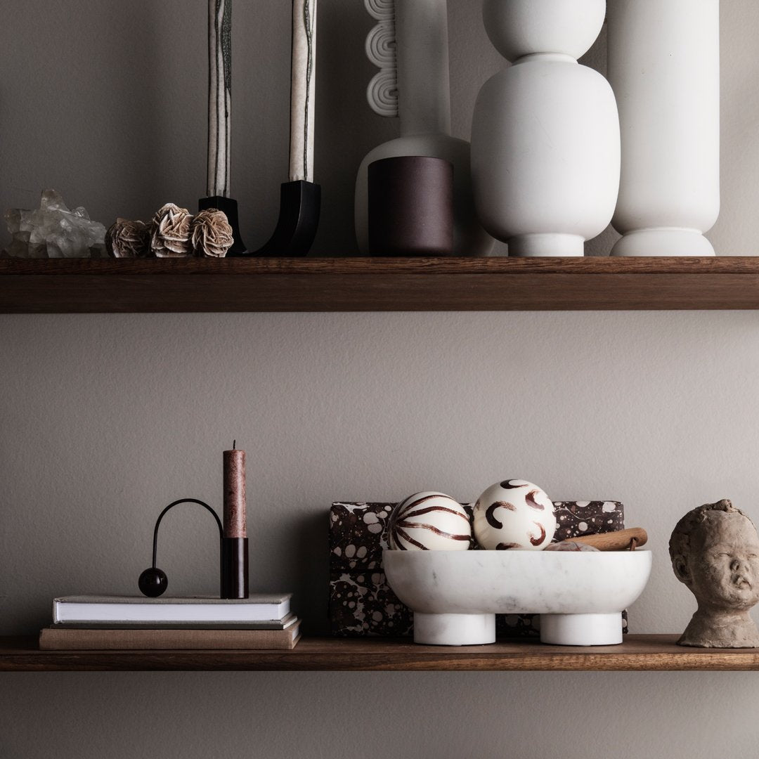 Minimalist shelf display featuring brown wood, textured white ceramics, and soft earthy tones with patterned decor accents.