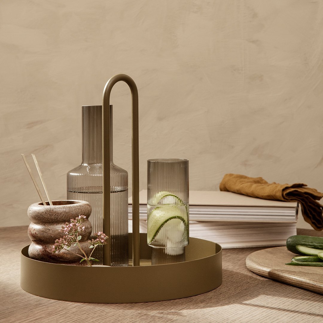 Elegant olive green tray with circular base, featuring minimalist glassware and textured stone accents.