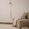 Neutral beige sofa with a checked pillow, complemented by a soft cream throw and a sleek gray wall lamp.