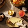 "Yellow speckled plate, vibrant orange bowl, black dish, and textured fabric create a warm, inviting dining scene."