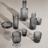 Set of smoky gray glassware featuring various shapes and textured patterns, perfect for elegant table settings.