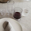 "Textured clear glass drinkware set with ribbed patterns, featuring various sizes on a neutral table setting."