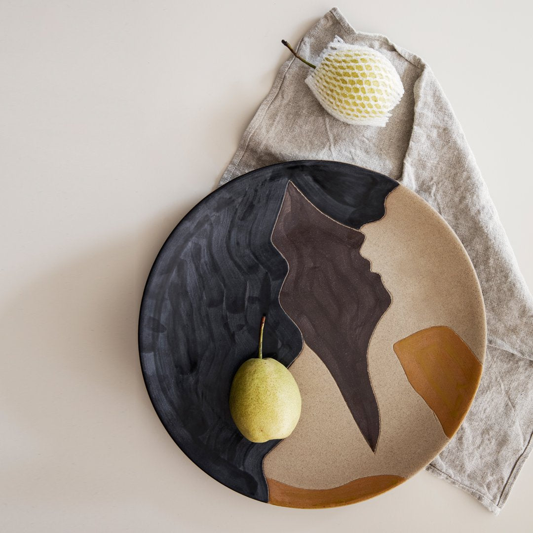 Abstract ceramic plate featuring earthy tones of brown, black, and beige with a modern artistic pattern.