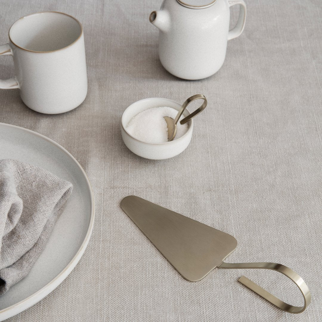 Elegant white ceramics and brushed brass accents on a neutral linen backdrop, showcasing a minimalist aesthetic.