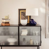 Modern black cabinet with frosted glass doors, featuring white, blue, and earthy tones in decor accents.